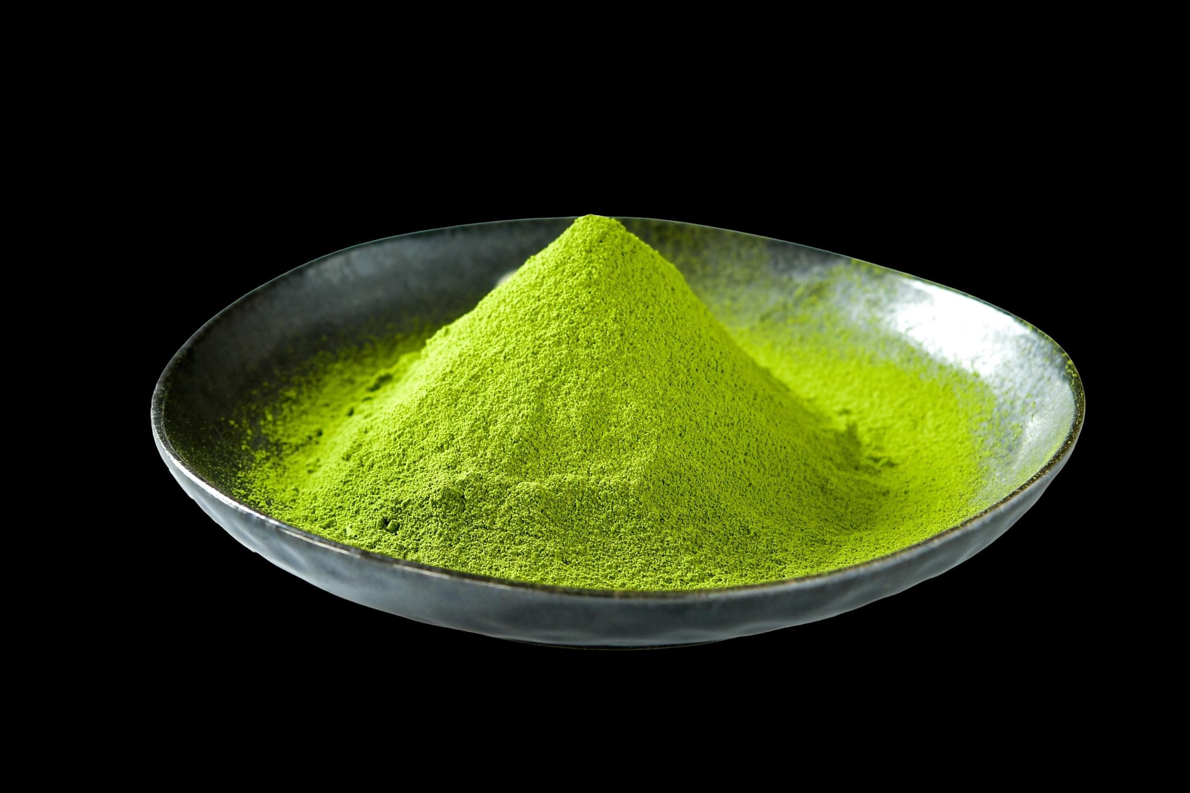 Fine mulberry powder mounded in a dark ceramic bowl